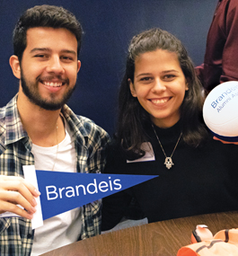A woman and a man, who is holding a small blue Brandeis pennant